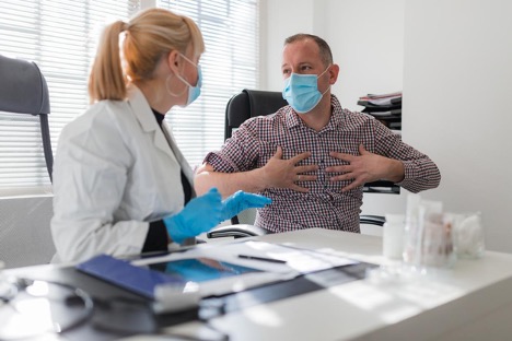 Doctor and patient discussing his illness while the patient is holding his chest